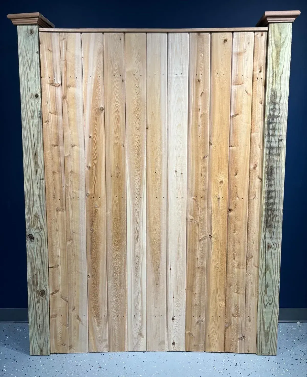 Wooden fence with vertical planks, framed by weathered posts and topped with a cap.