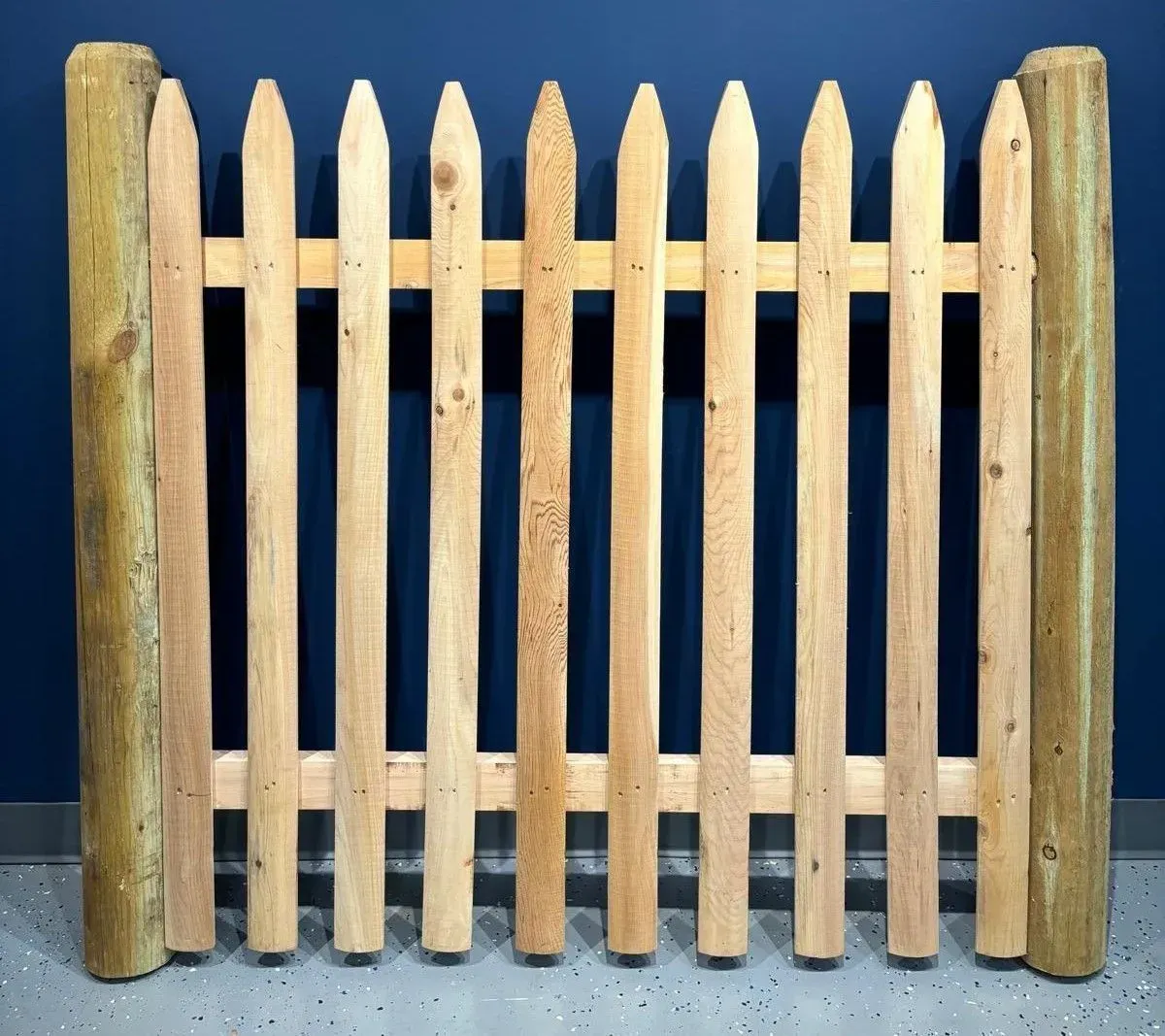 Wooden picket fence with rounded posts against a dark blue background.